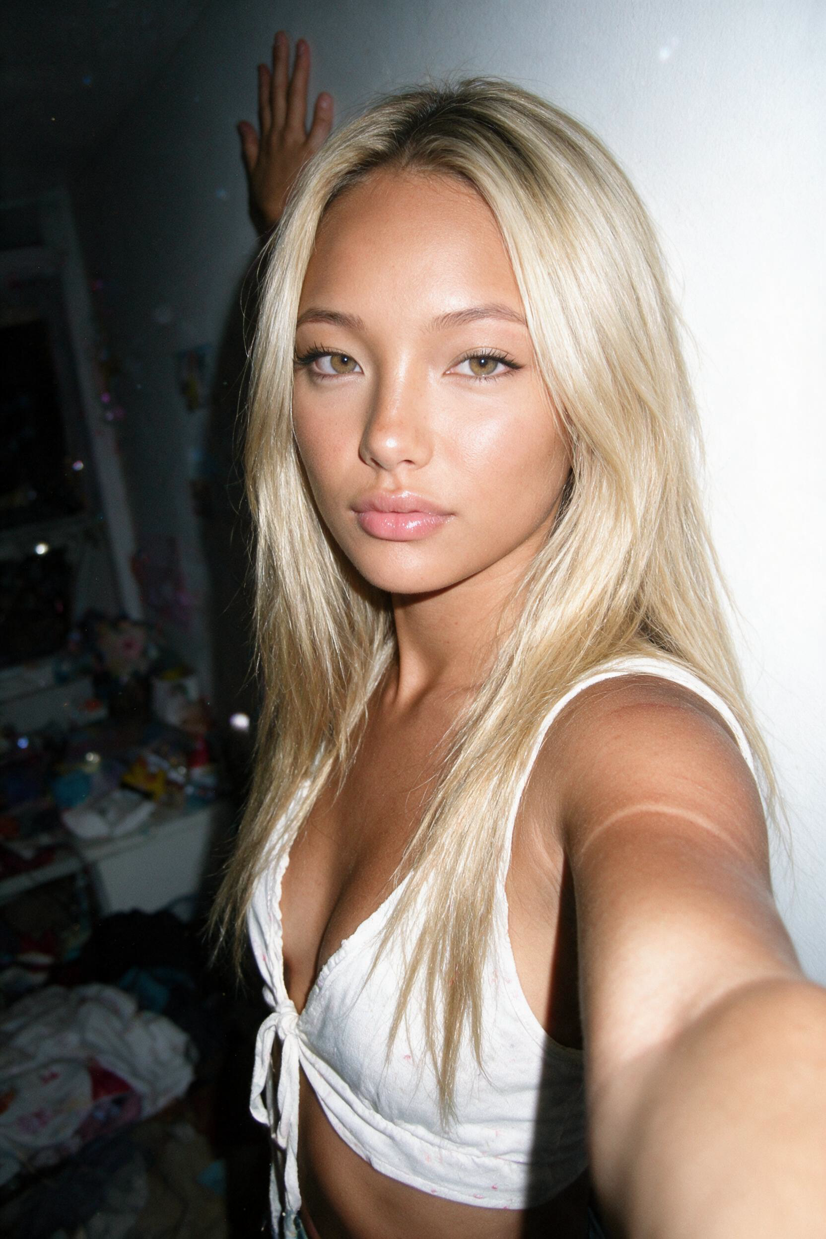 blonde hair asian — A young woman strikes playful poses in her casual bedroom, modeling various summer outfits and showing off her tan lines — 2